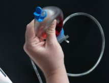 Keeping the bulb squeezed, hold the drain opening pointing up and away from you. Open the cap.